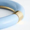 Bracciale rigido in resina con dettagli in metallo a contrasto